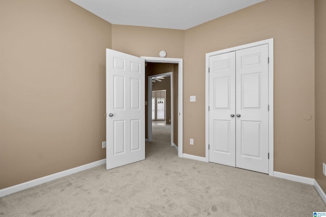 unfurnished bedroom featuring light carpet, a closet, and baseboards