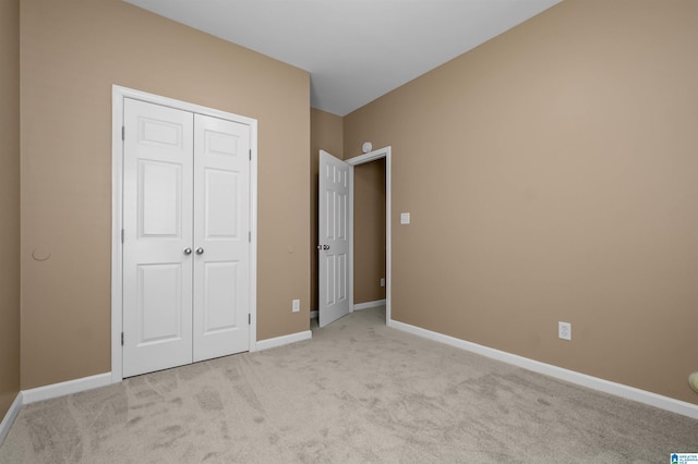 unfurnished bedroom with light carpet, a closet, and baseboards