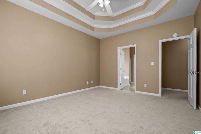 unfurnished bedroom with a ceiling fan, baseboards, ornamental molding, a raised ceiling, and light colored carpet