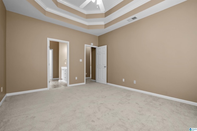 spare room with visible vents, baseboards, light colored carpet, a tray ceiling, and ornamental molding