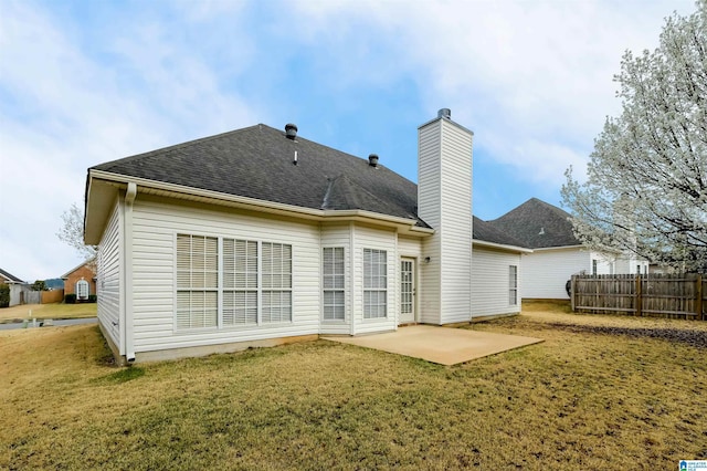 back of property with a lawn, a patio, fence, a shingled roof, and a chimney