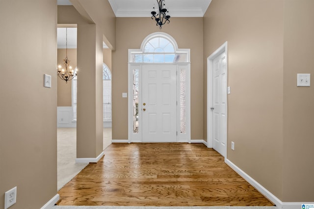 foyer with baseboards, wood finished floors, a chandelier, and ornamental molding