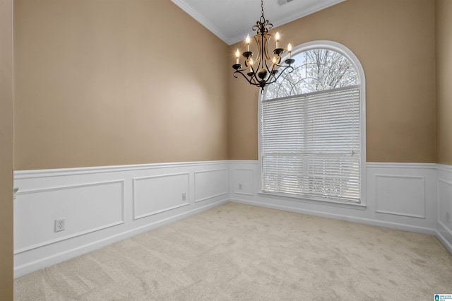 empty room featuring ornamental molding, carpet, wainscoting, and a chandelier