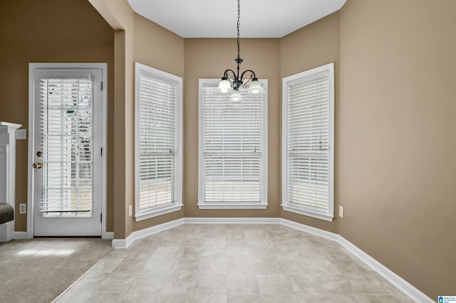 unfurnished dining area featuring an inviting chandelier, plenty of natural light, and baseboards