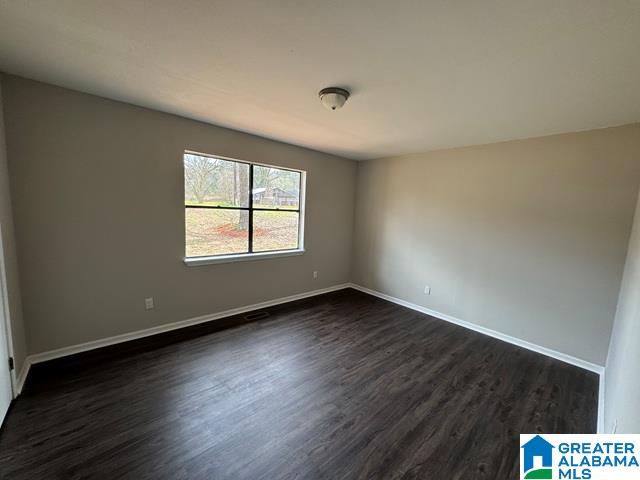 empty room with baseboards and dark wood-style flooring