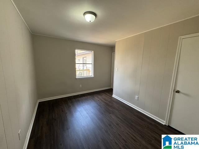 unfurnished room with dark wood-type flooring and baseboards