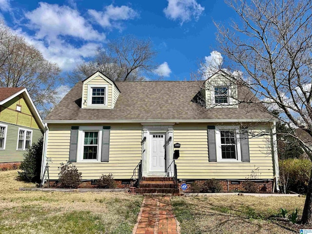 cape cod house with entry steps, a front yard, a shingled roof, and crawl space