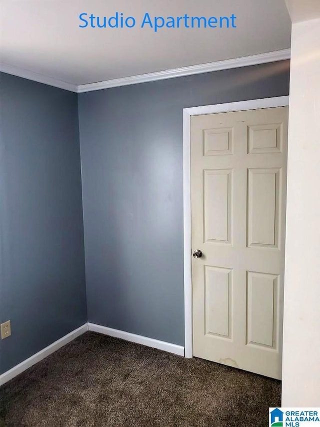 spare room with dark colored carpet, baseboards, and crown molding