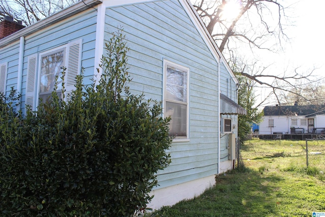 view of side of home with a lawn, a chimney, and fence