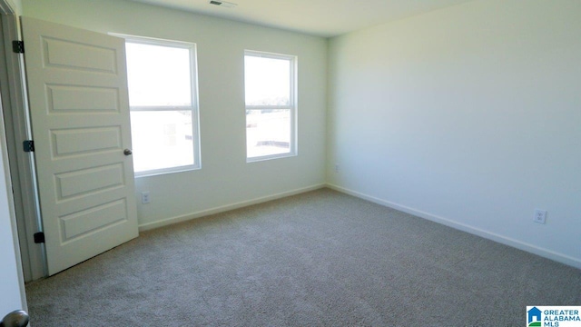 empty room with baseboards, visible vents, and carpet floors