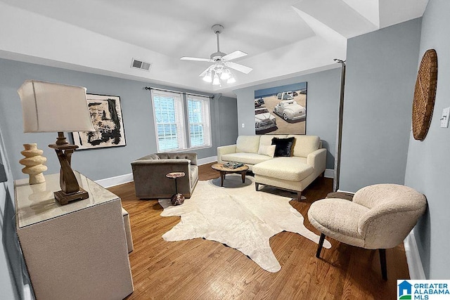 living room featuring a ceiling fan, wood finished floors, visible vents, and baseboards