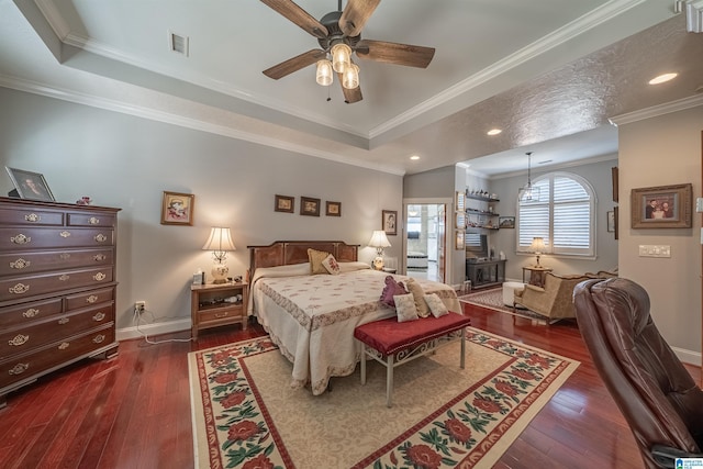 bedroom with a tray ceiling, crown molding, dark wood-style floors, and visible vents