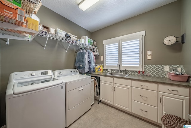 washroom with a sink, light tile patterned flooring, cabinet space, a textured ceiling, and separate washer and dryer