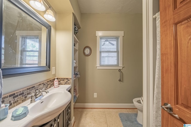 bathroom with tile patterned flooring, a healthy amount of sunlight, toilet, and tasteful backsplash