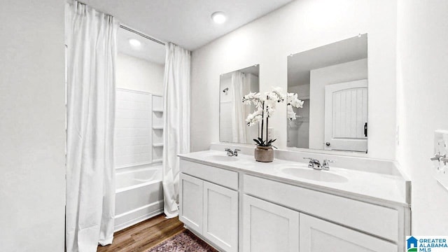 full bathroom with double vanity, wood finished floors, shower / tub combo with curtain, and a sink