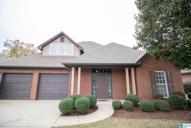 view of front of property featuring brick siding, roof with shingles, concrete driveway, and an attached garage