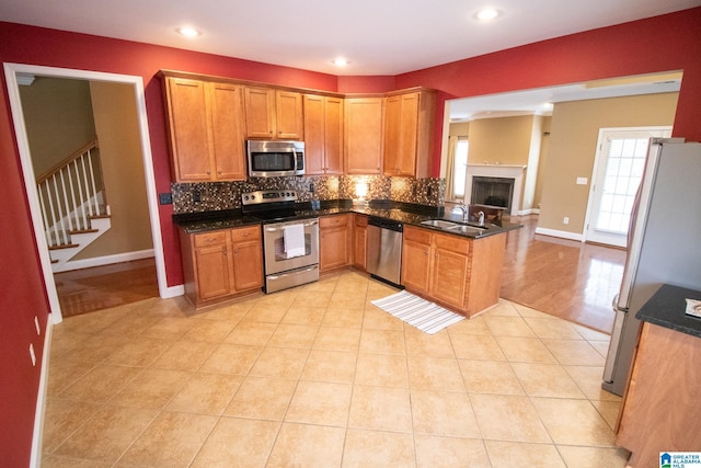 kitchen featuring light tile patterned floors, a sink, stainless steel appliances, brown cabinets, and backsplash