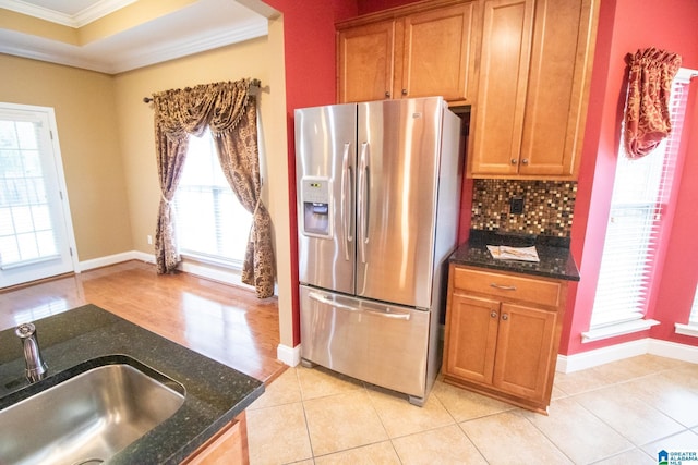 kitchen featuring ornamental molding, stainless steel refrigerator with ice dispenser, a sink, a tray ceiling, and decorative backsplash