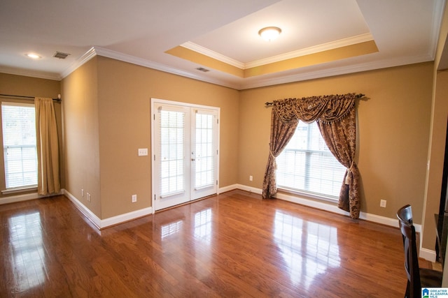 empty room featuring crown molding, baseboards, french doors, dark wood-style floors, and a raised ceiling