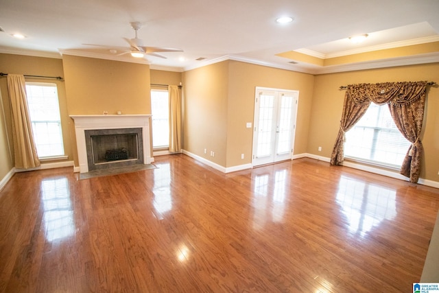 unfurnished living room featuring a high end fireplace, baseboards, a ceiling fan, and wood finished floors