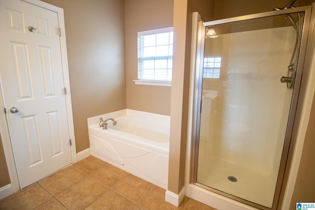 full bathroom featuring tile patterned floors, a bath, baseboards, and a stall shower