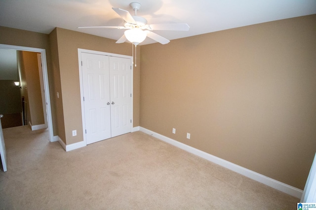 unfurnished bedroom with a closet, light colored carpet, baseboards, and ceiling fan