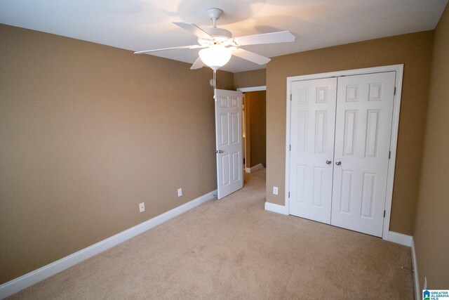 unfurnished bedroom featuring a closet, baseboards, light carpet, and a ceiling fan