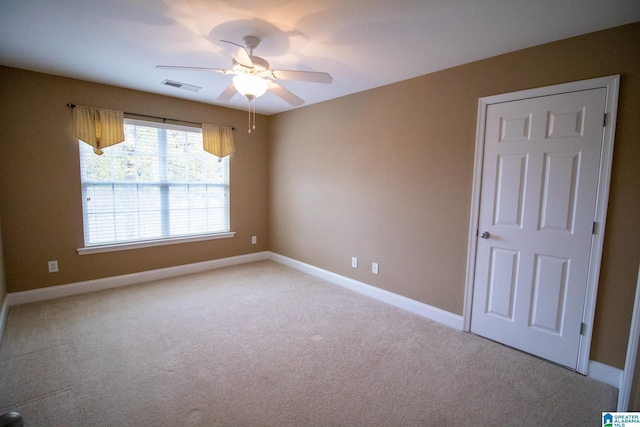 unfurnished room with baseboards, light colored carpet, visible vents, and ceiling fan