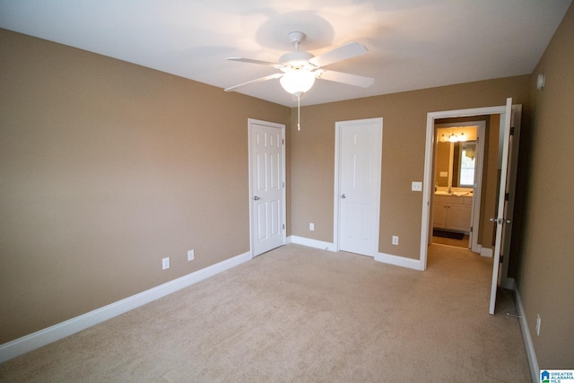 unfurnished bedroom featuring a ceiling fan, baseboards, light colored carpet, and ensuite bathroom