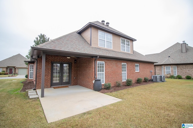 rear view of property featuring brick siding, a shingled roof, french doors, a yard, and a patio