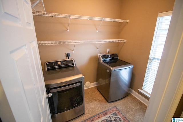 washroom featuring baseboards, separate washer and dryer, and laundry area