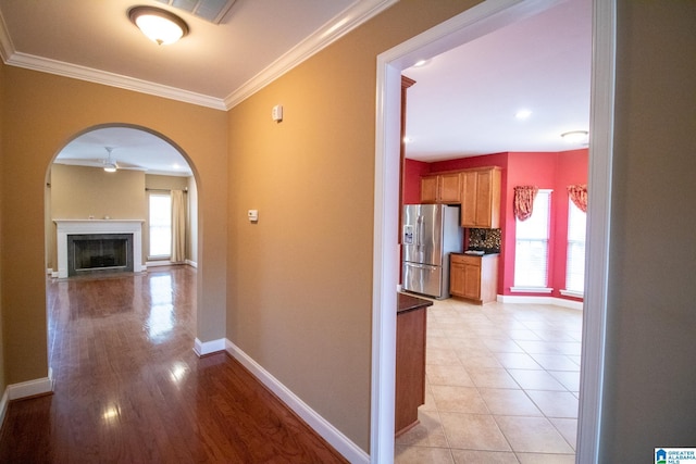 hall with baseboards, a wealth of natural light, and ornamental molding