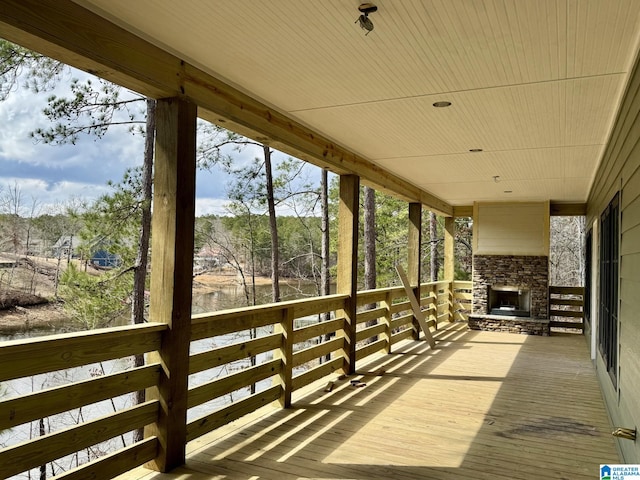 wooden deck with an outdoor stone fireplace