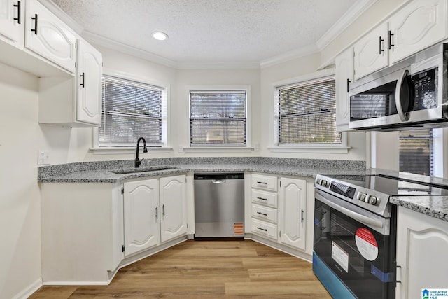 kitchen with crown molding, light wood-type flooring, stainless steel appliances, a textured ceiling, and a sink