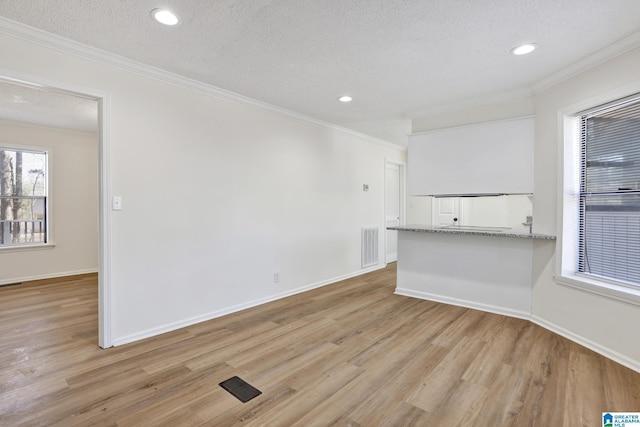 interior space with ornamental molding, baseboards, light wood-type flooring, and a textured ceiling