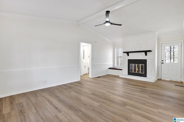 unfurnished living room with a large fireplace, light wood-style floors, ceiling fan, and vaulted ceiling with beams