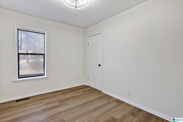 spare room featuring visible vents, crown molding, baseboards, wood finished floors, and a textured ceiling