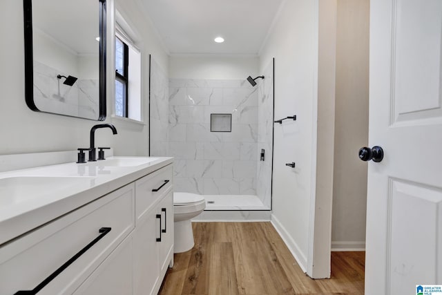 bathroom featuring a tile shower, toilet, and wood finished floors