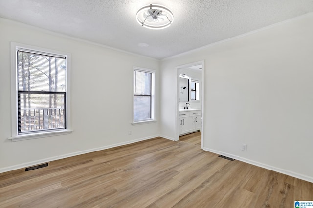 spare room with light wood finished floors, visible vents, and a wealth of natural light