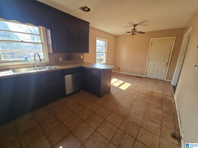 kitchen featuring light tile patterned floors, a ceiling fan, a peninsula, a sink, and dishwasher