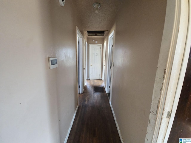 hall featuring dark wood-type flooring, baseboards, and a textured ceiling