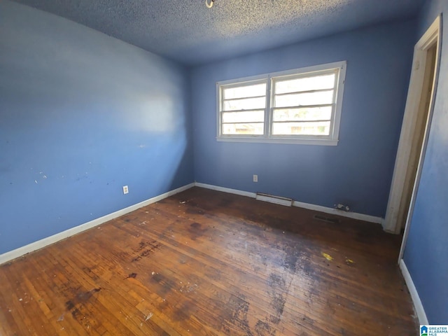 unfurnished bedroom with visible vents, baseboards, a textured ceiling, and hardwood / wood-style floors