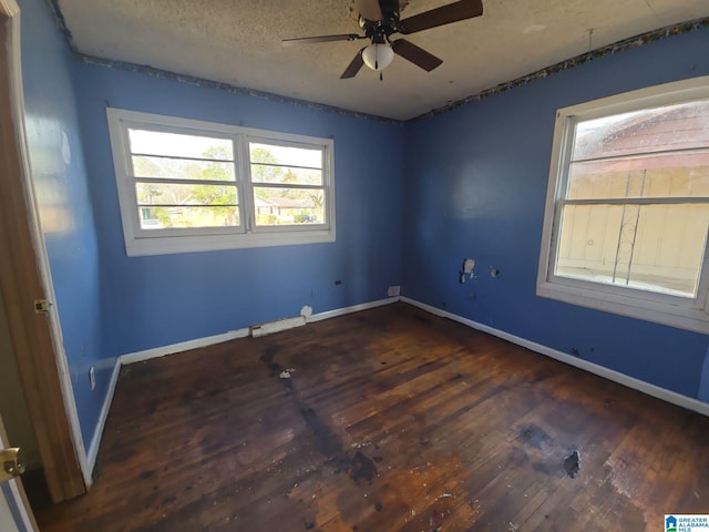 unfurnished room with ceiling fan, a textured ceiling, baseboards, and wood finished floors