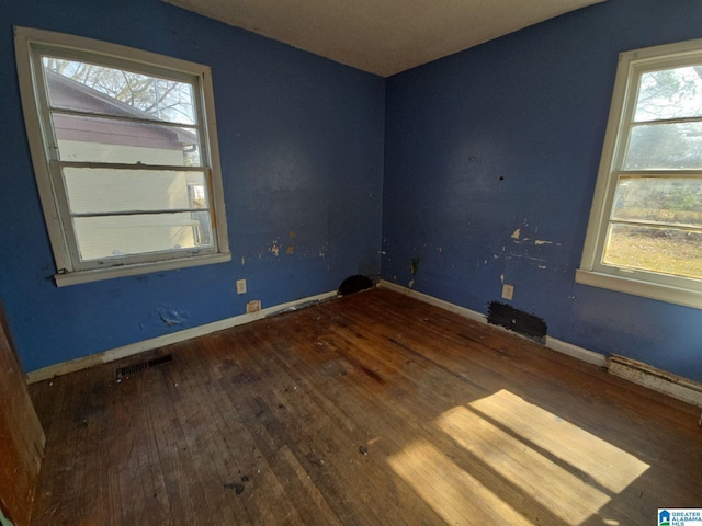 empty room featuring visible vents, baseboards, and hardwood / wood-style floors