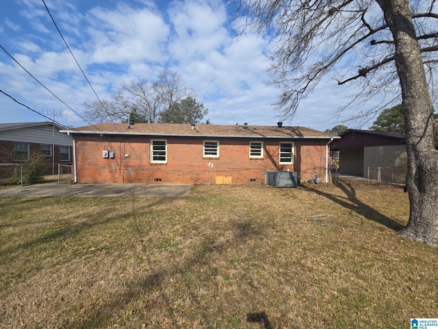 rear view of house featuring crawl space, a lawn, brick siding, and fence