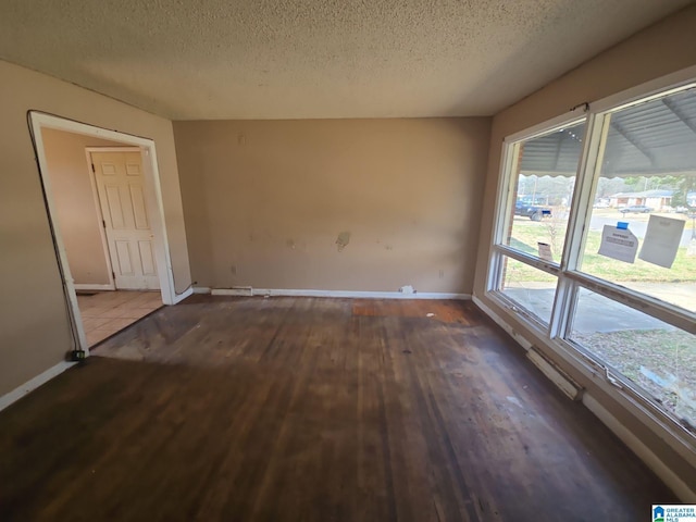 spare room with wood finished floors, baseboards, and a textured ceiling