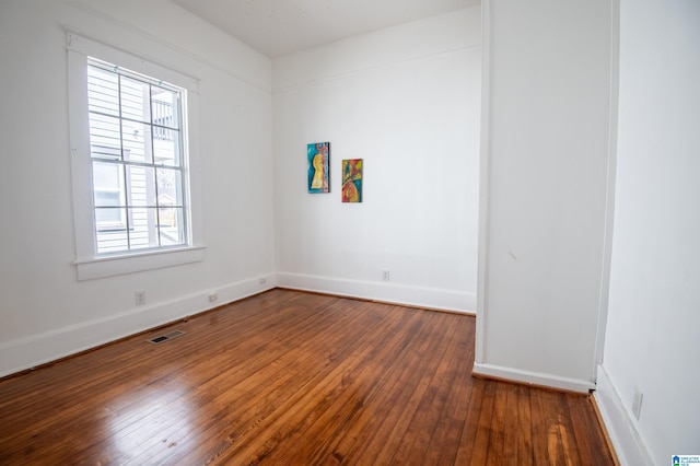 empty room featuring visible vents, baseboards, and hardwood / wood-style floors