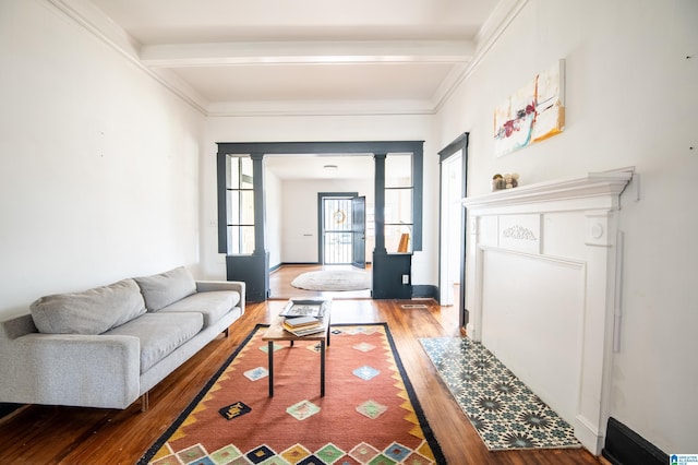 living room featuring beam ceiling, crown molding, ornate columns, and wood finished floors