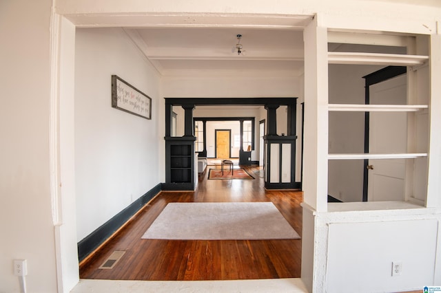 hallway with visible vents, beamed ceiling, baseboards, and wood finished floors