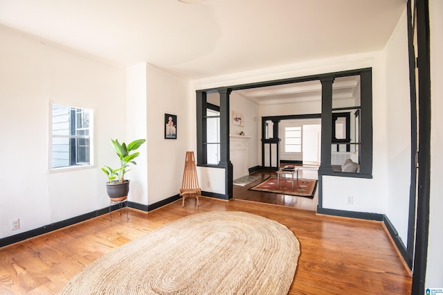 interior space featuring wood finished floors, baseboards, and ornate columns